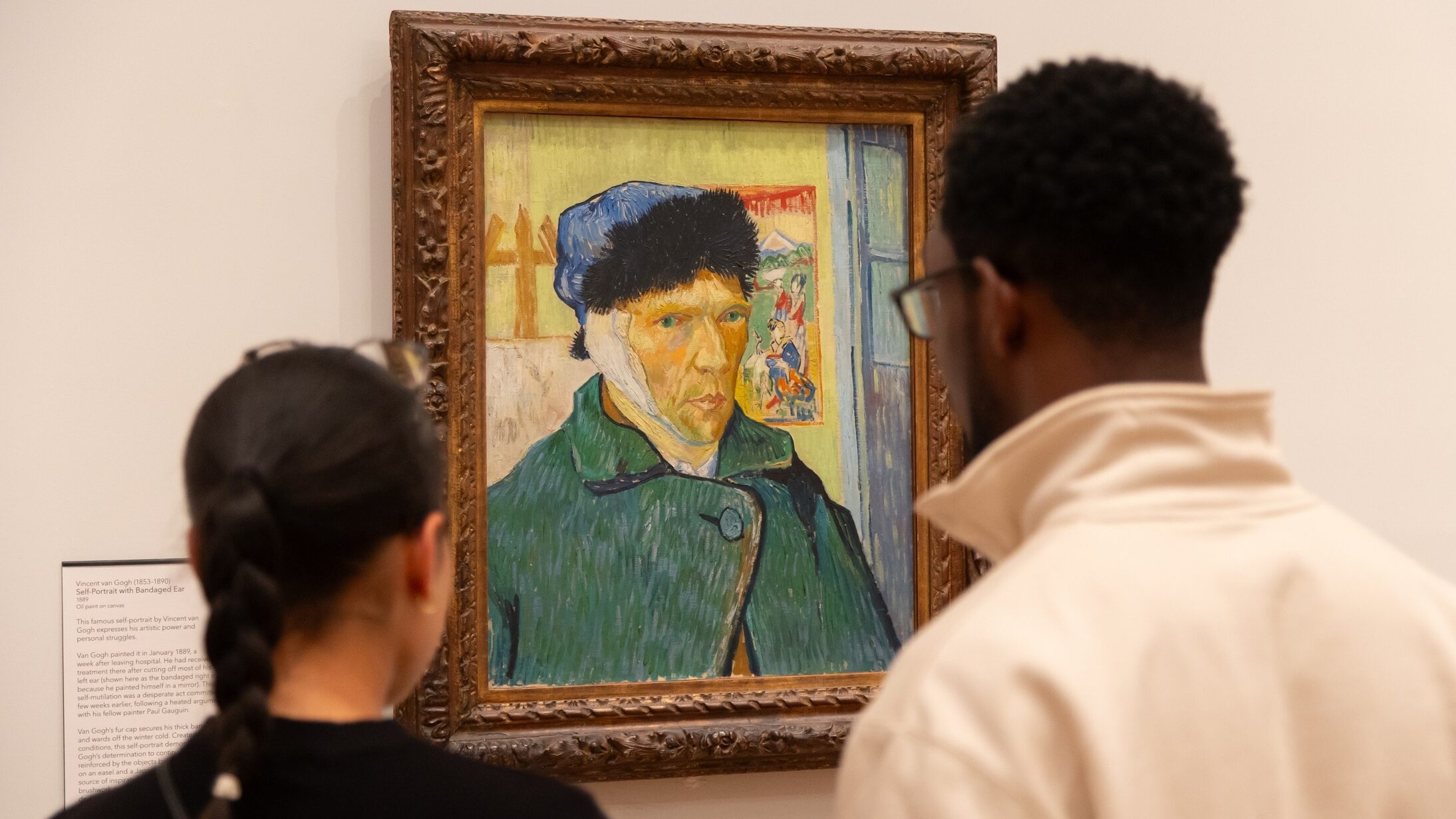 Two visitors look at Van Gogh's self portrait with bandaged ear